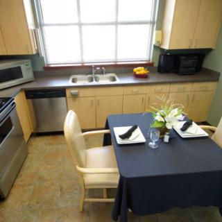 A cozy kitchen with a small dining area featuring modern appliances and a table set for two.