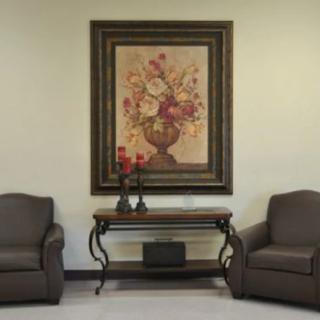 A cozy seating area featuring two chairs, a decorative table, and a floral painting on the wall.
