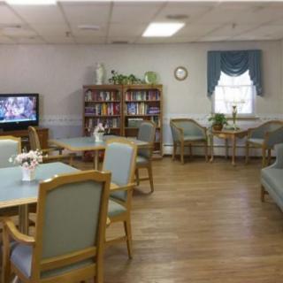 A cozy common room with seating, a television, and a bookshelf.