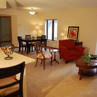 A cozy living room and dining area featuring modern furniture and warm lighting.