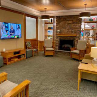 A cozy living room featuring a stone fireplace, television, and comfortable seating surrounded by bookshelves.