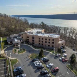 Aerial view of a building with a parking lot by the river.