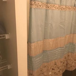 A cozy bathroom featuring a blue and beige shower curtain with floral patterns.