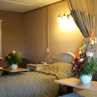 A cozy hospital room with warm lighting, featuring two beds adorned with floral arrangements.