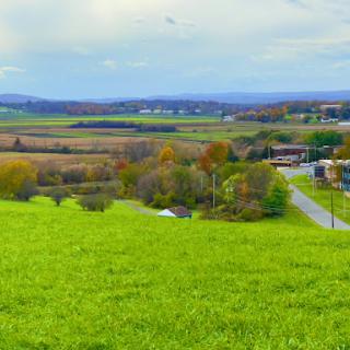 A scenic view of lush green fields and rolling hills under a cloudy sky.