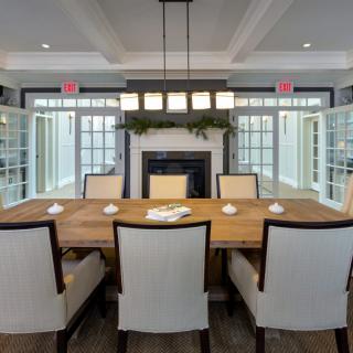 A modern dining room with a wooden table, upholstered chairs, and a fireplace.