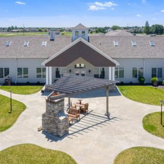A large building with a central patio area and surrounding lawn under a clear blue sky.