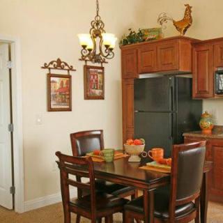 A cozy kitchen and dining area with wooden cabinets, a dining table set for four, and decorative elements including a rooster figurine.