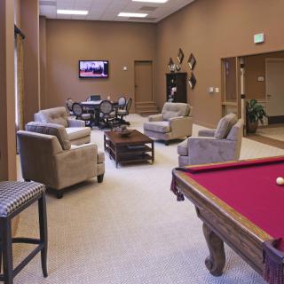 A comfortable lounge area with a pool table, plush chairs, and a television.