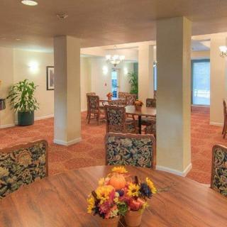 A cozy dining area with several tables and chairs, adorned with floral decor and ambient lighting.
