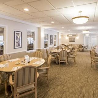 A well-lit dining room with multiple tables and chairs, featuring a cozy interior design.