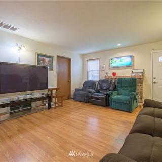 A cozy living room with a large television, comfortable seating, and hardwood floors.