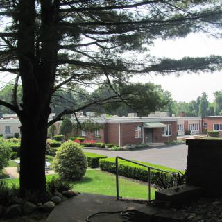 A scenic view of a landscaped area with buildings, surrounded by trees and greenery.