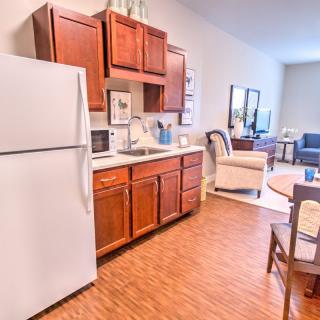 A cozy kitchen area with wooden cabinets, a refrigerator, and a view into a connected living space.