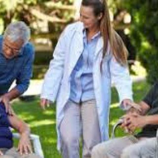 A caregiver attending to elderly individuals in a garden setting.