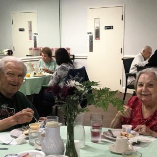 Elderly individuals enjoying a meal together in a communal dining area.
