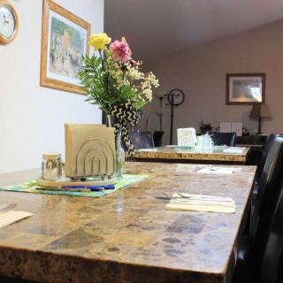 A dining room with a marble table, decorated with flowers and place settings.