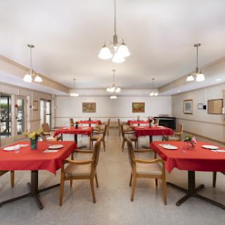 A bright and inviting dining room set up with red tablecloths, ready for a meal.