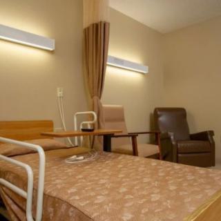 A hospital room with a bed, chairs, and a privacy curtain.