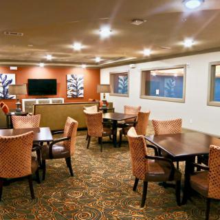 A well-lit dining area with multiple tables and chairs, featuring a patterned carpet and modern decor.