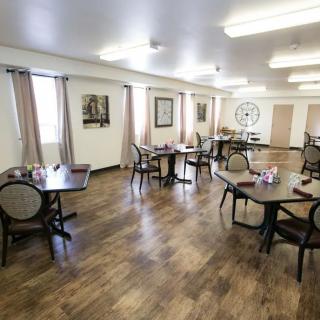 A spacious dining room with neatly arranged tables and chairs on a wooden floor.