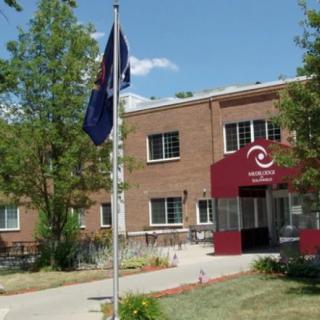 A brick building with a flagpole and trees under a clear blue sky.