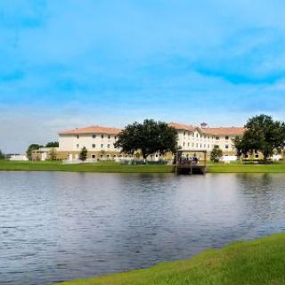 A scenic view of a large building by the lake on a clear day.