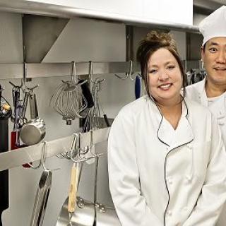 Two chefs posing in a professional kitchen.