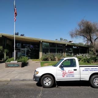 A pickup truck parked in front of a modern building with an American flag.