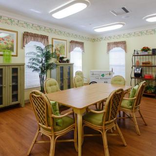 A cozy meeting room with wicker chairs and a wooden table, adorned with plants and decorated with art on the walls.