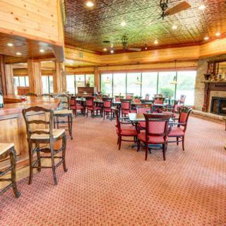 A warm and inviting restaurant interior featuring wooden decor, with tables and chairs arranged on a carpeted floor alongside a cozy fireplace.