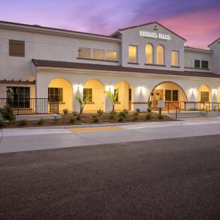 A well-lit Mediterranean-style building at dusk with an inviting entrance.