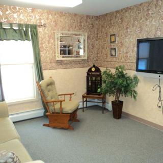 A cozy living room with a rocking chair, television, and decorative wallpaper.
