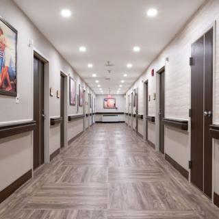 A well-lit hallway with artwork on the walls and doors lining both sides.