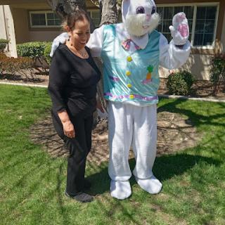 A person posing with the Easter Bunny costume in a sunny outdoor setting.