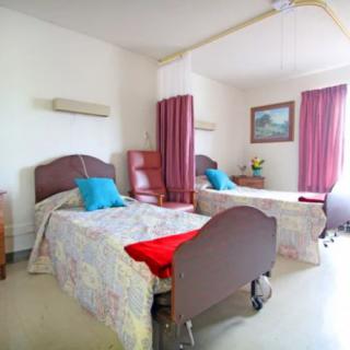 A hospital room with two beds separated by a privacy curtain.