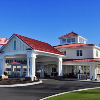 A modern building with a red roof and a prominent entrance featuring columns, under a clear blue sky.