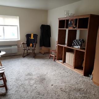 A spacious, minimally furnished living room with wooden shelves and a cozy atmosphere.