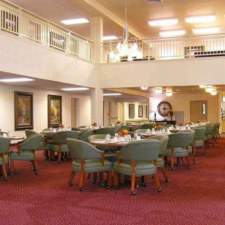 A spacious dining room with multiple tables and chairs, adorned with chandeliers and elegant decor.