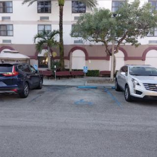 A view of a parking lot with two parked cars and a building in the background.