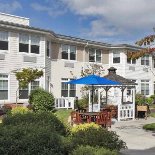 A residential building with a landscaped garden and a gazebo under a clear sky.
