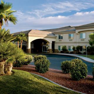 A hotel building with palm trees and landscaped surroundings.