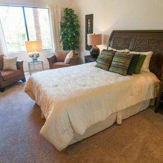 A cozy and well-decorated bedroom with a large bed, cushioned chairs, and ample natural light.