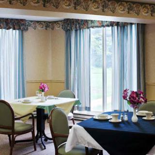 A cozy dining area featuring neatly set tables and natural light streaming through the windows.