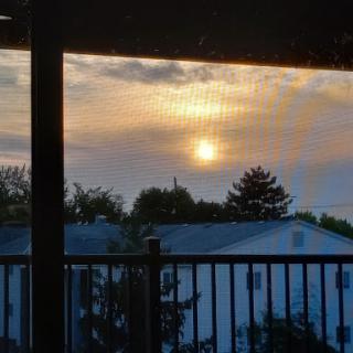A beautiful sunset viewed from a cozy balcony, casting a warm glow over the rooftops.
