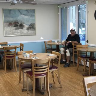 A quiet cafe with empty tables and a man sitting near the window.