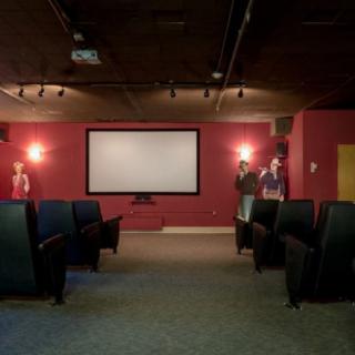 A cozy home theater with red walls, a large screen, and comfortable seating.
