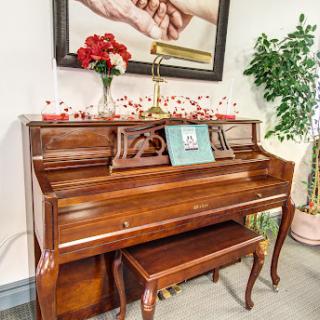 A beautifully polished wooden piano accompanied by decorative elements and a piece of art on the wall.
