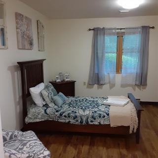 A cozy bedroom with a single bed, decorated with patterned bedding and complemented by soft curtains.