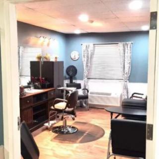 A cozy hair salon interior with chairs, a desk, and mirrors.